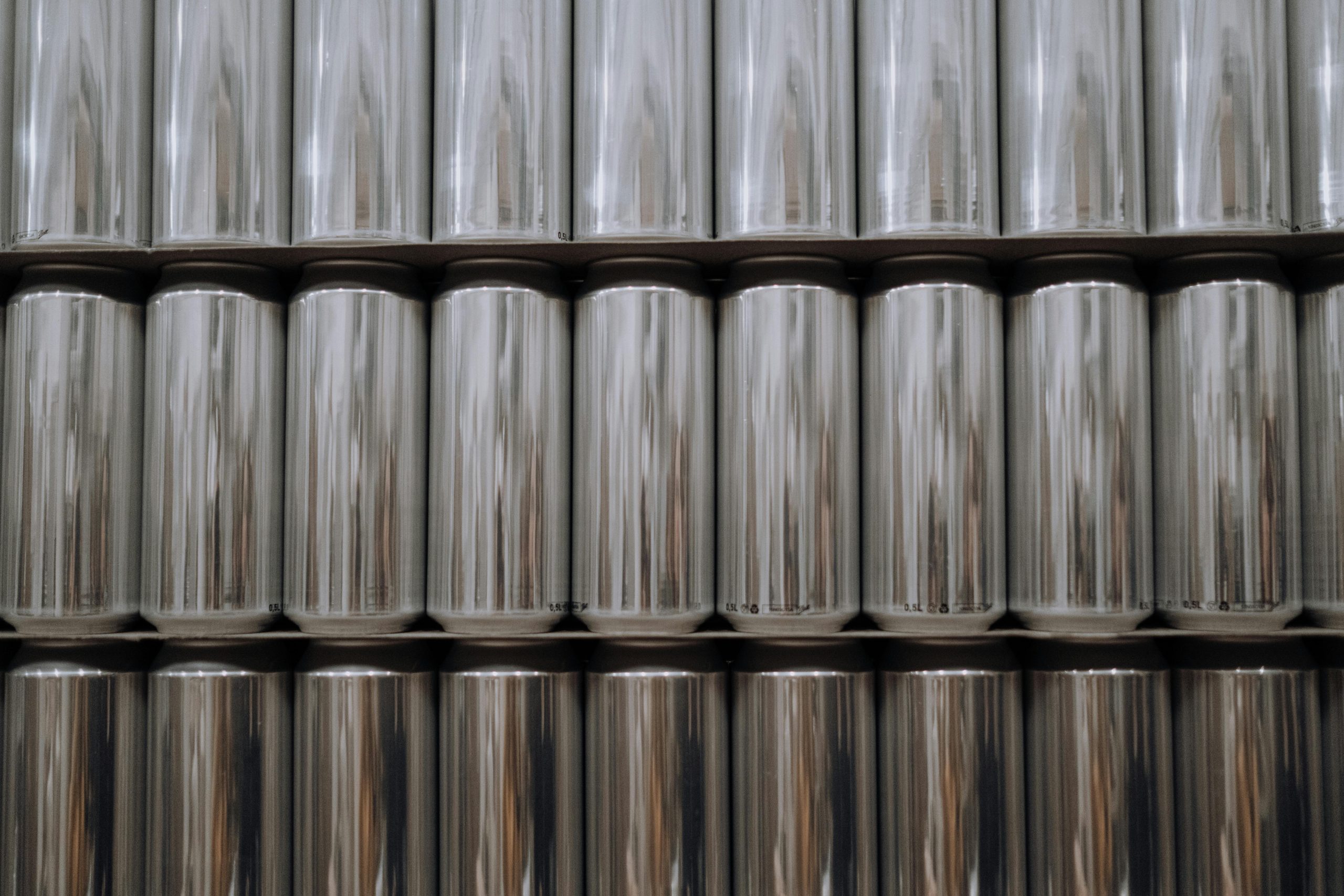 A neatly organized stack of reflective aluminum beverage cans in an industrial setting.