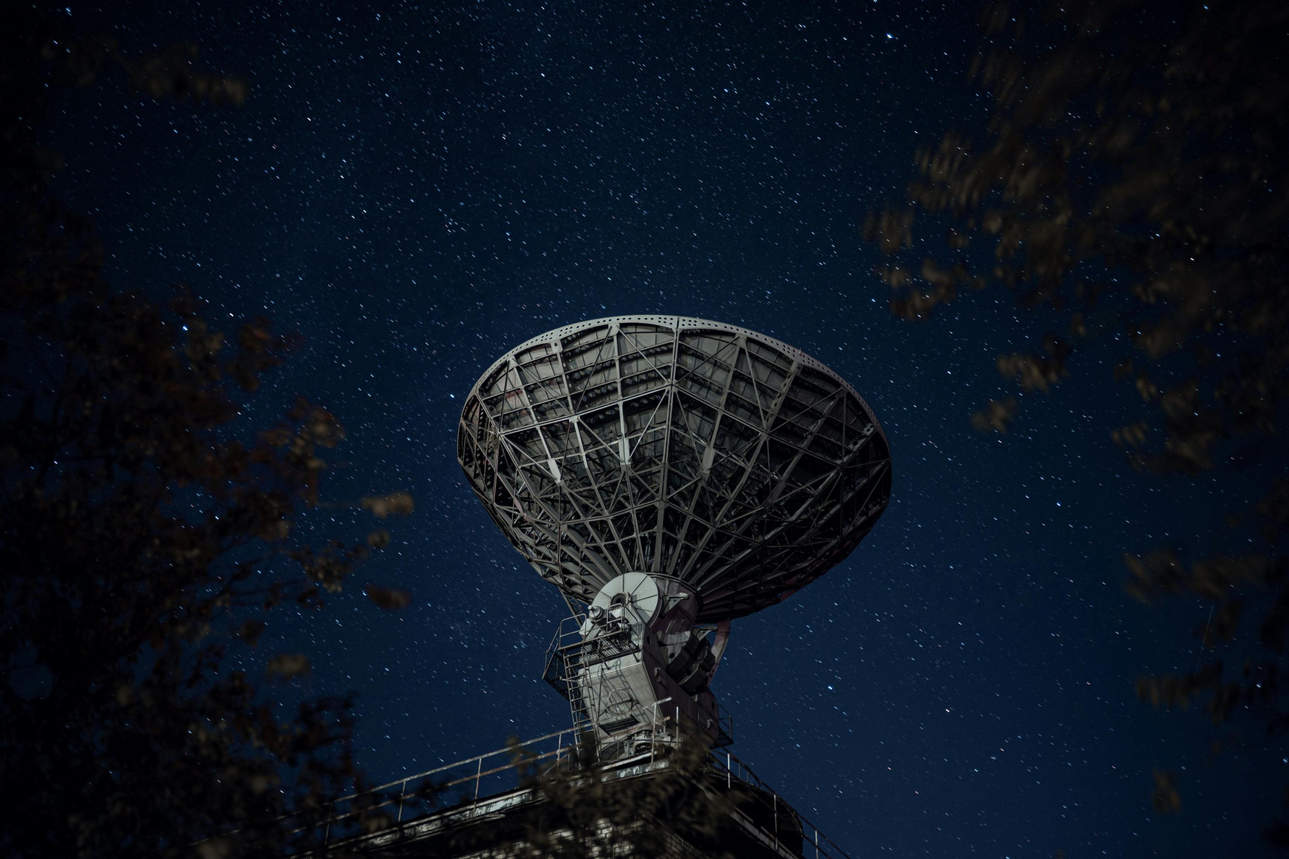 A large radio telescope beneath a starry night sky capturing celestial signals.